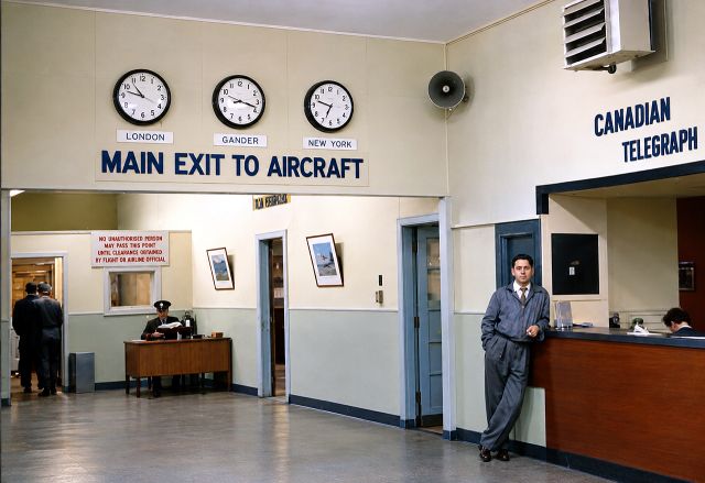 The Main Exit to Aircraft hall, with clocks showing the time in London, Gander and New York, and a man standing at the Canadian Telegraph counter